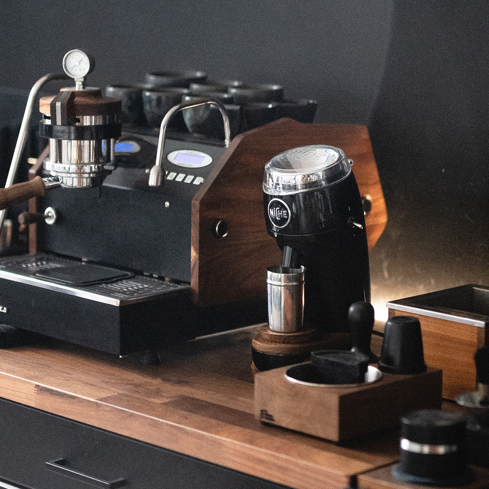 Black Niche Zero on brew bar next to espresso machine