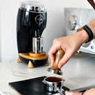 Tamping coffee with Black Niche Duo in background