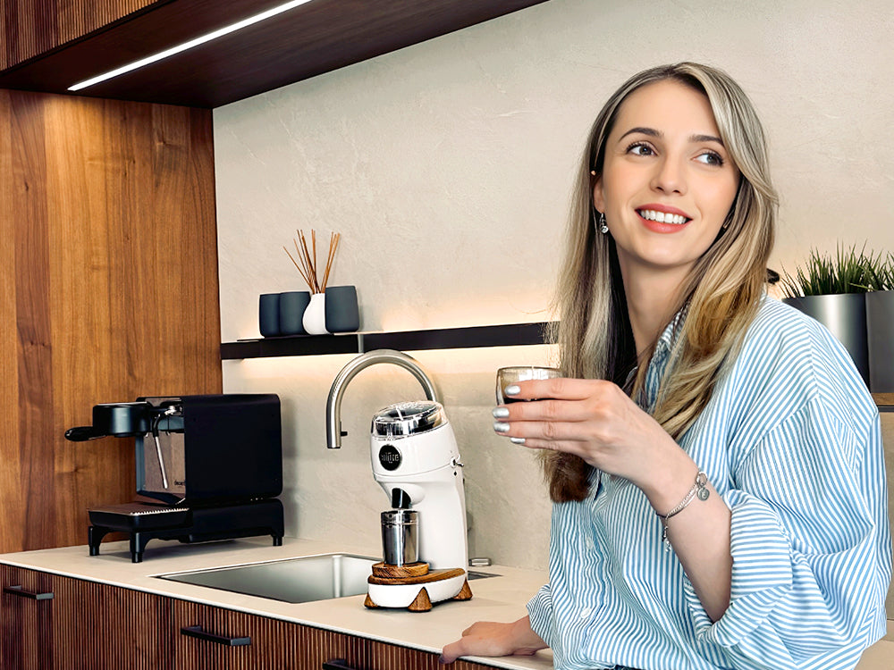 Woman smiling and holding glass of coffee next to white Niche Zero
