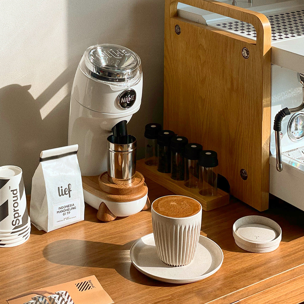 White Niche Zero next to espresso machine with freshly made coffee in front