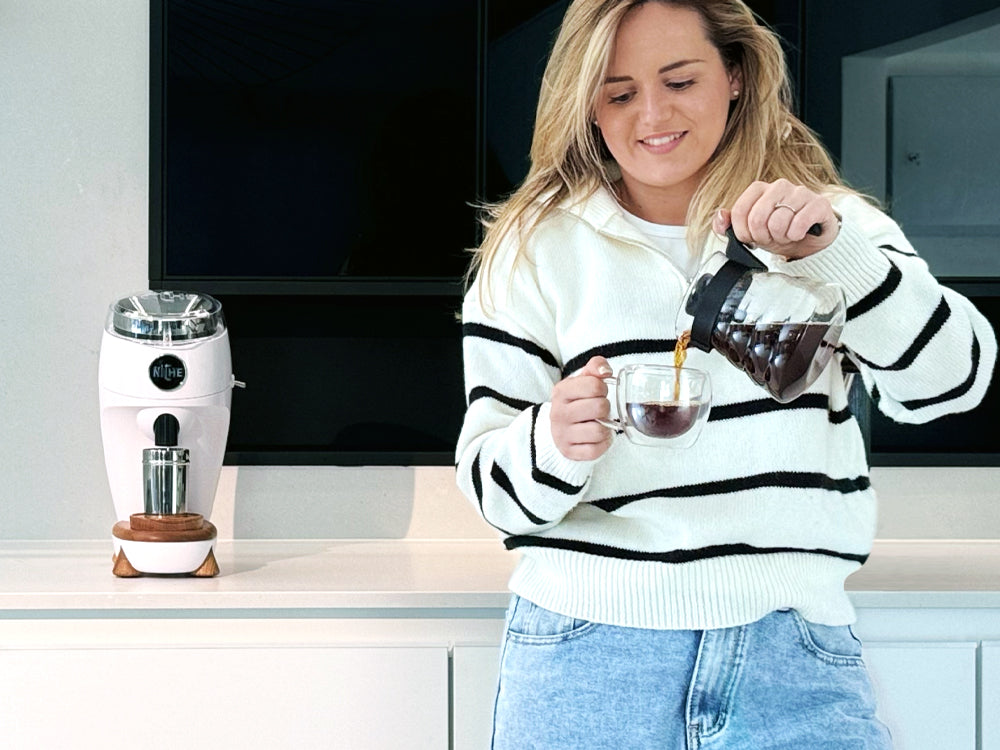 Woman pouring filter coffee into glass next to White Niche Duo